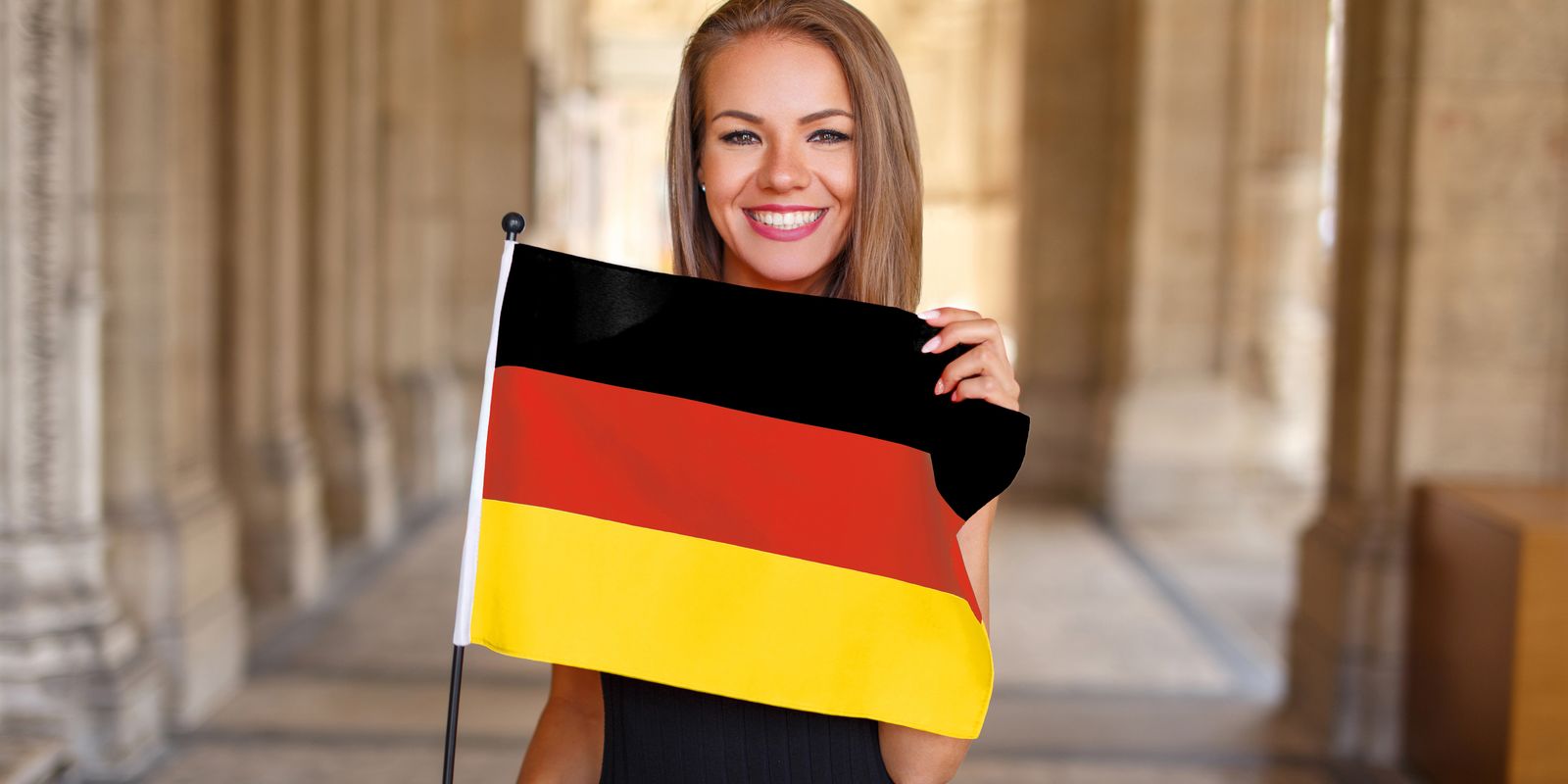 eine lächelnde Frau hält eine deutsche Flagge in ihren Händen